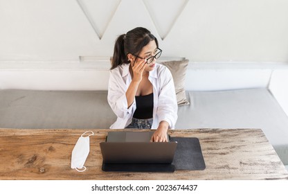 Beautiful Young Asian Woman With Glasses Using And Working On A Laptop Computer In A Cafe.
