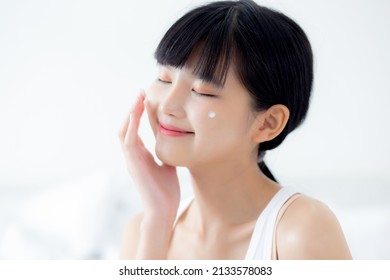 Beautiful Young Asian Woman Happy Applying Cream Or Lotion With Moisturizer To Skin On Face, Beauty Asia Girl Applying Skincare Touch Facial With Cosmetic Makeup, Skin Care And Health Concept.