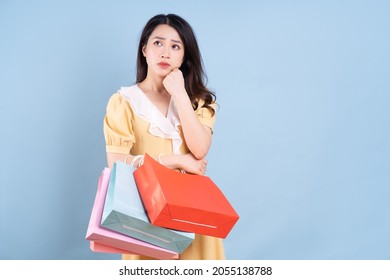 Beautiful Young Asian Woman Holding Shopping Bag On Blue Background