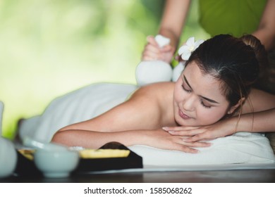 Beautiful Young Asian Woman Lying Relaxing And Smile On The Bed Having A Massage With Herbal Compresses In A Spa. Thai Massage For Health.