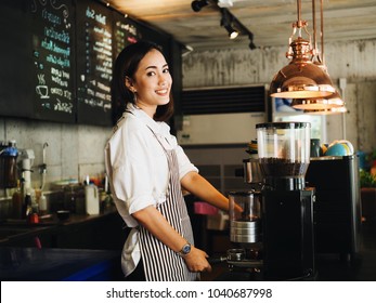 Beautiful young Asian woman making a coffee cup in cafe.