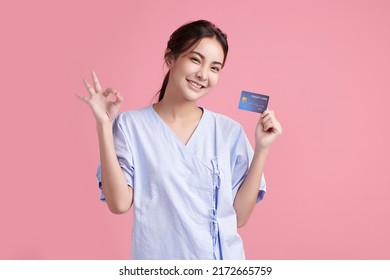 Beautiful Young Asian Woman Patient Showing Credit Card On Pink Background, Insurance Card Concept.