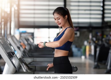 Beautiful Young Asian Woman Preparing To Set Up Watch Before Running In Machine Treadmill At Fitness Gym Club.