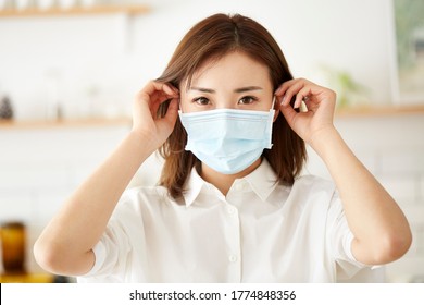 beautiful young asian woman putting on a mask on face - Powered by Shutterstock