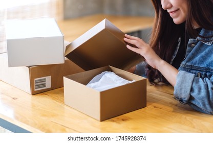 A Beautiful Young Asian Woman Receiving And Opening A Postal Parcel Box At Home For Delivery And Online Shopping Concept