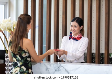 Beautiful Young Asian Woman Receptionists Working At A Reception Desk And Holding Credit Card For Customer Paying.