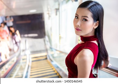 Beautiful young asian woman in red dress going down the escalator in shopping mall . happy elegant lady . copy space - Powered by Shutterstock