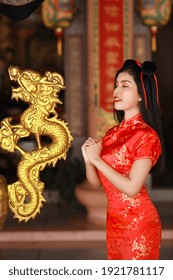 Beautiful young Asian woman in red Chinese dress traditional cheongsam qipao with gesture of congratulation and happy smiling face, she standing in front of ancient temple (Chinese new year concept) - Shutterstock ID 1921781117