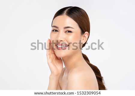 Beautiful young Asian woman smiling with hand touching face isolated on white background for beauty and skin care concepts