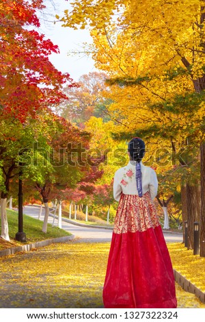 Beautiful Young Asian woman traveler in Korean national dress or Hanbok traveling into the Olympic park,Seoul in Seoul,South Korea. Autumn season 