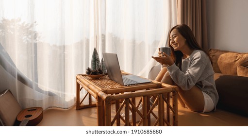 A Beautiful Young Asian Woman Using Laptop Computer For Video Call While Sitting And Drinking Coffee At Home