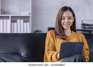 Beautiful Young Asian woman using tablet laptop computer on sofa at home, shopping online with internet in happy mood and Relax part time concept - Powered by Shutterstock