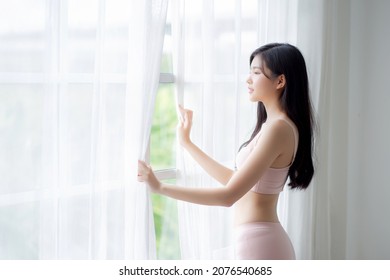 Beautiful Young Asian Woman Wake Up And Walking To Window With Open Curtain In The Morning With Cozy, Sexy Girl In Underwear Smiling Relax And Resting In The Vacation With Happy, Lifestyle Concept.