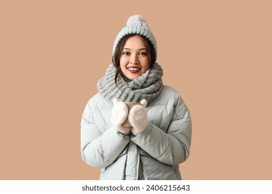 Beautiful young Asian woman in warm scarf with cup of tea on brown background - Powered by Shutterstock