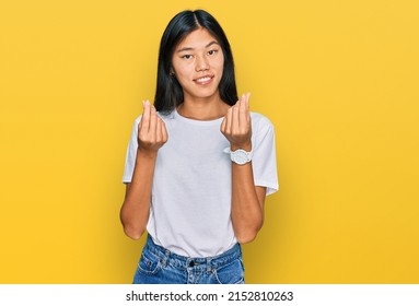 Beautiful Young Asian Woman Wearing Casual White T Shirt Doing Money Gesture With Hands, Asking For Salary Payment, Millionaire Business 