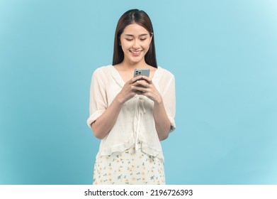 Beautiful young asian woman in white dress with flower pattern using smartphone isolated on blue background - Powered by Shutterstock