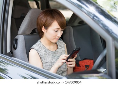 Beautiful Young Asian Woman Who See A Smart Phone In A Car