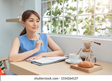 Beautiful Young Asian Woman Writing To Do List While Sitting The Window