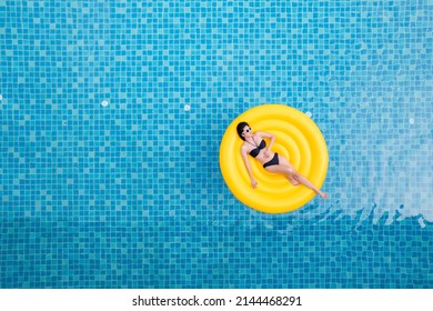 Beautiful Young Asian Woman With Yellow Inflatable Ring Relaxing In Swimming Pool. Top View