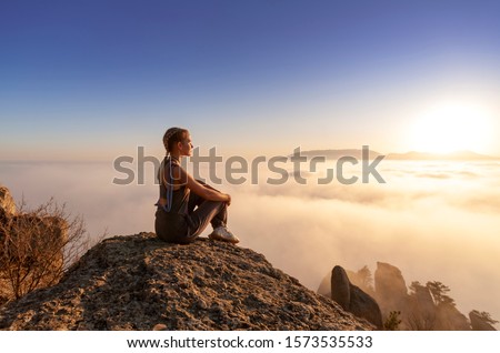 beautiful young athletic girl looking at the sun in the mountains, view from the back, the end of togetherness with nature