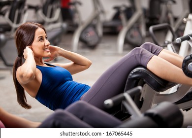 Beautiful young athletic woman doing some crunches in a bench at the gym