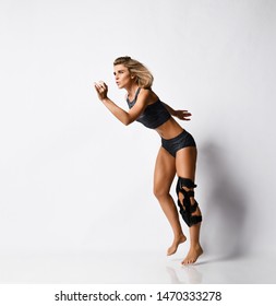 Beautiful Young Athletic Woman With A Knee Bandage Playing Sports Gymnastics Yoga, Recovery After Injury. Isolated