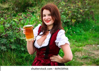 Beautiful, young, Bavarian woman in dirndl holding beer glass
