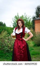 Beautiful, young, Bavarian woman in dirndl holding beer glass