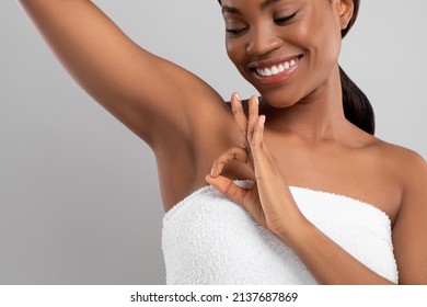 Beautiful Young Black Female Showing Her Smooth Armpit And Ok Gesture, Happy African American Woman Lifting Hand, Enjoying Underarm Depilation Result, Standing On Gray Studio Background, Copy Space
