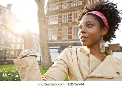 Beautiful Young Black Woman Holding The Sun Between Her Fingers At Sunset While Visiting London City.