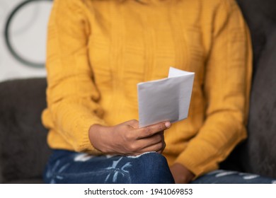 Beautiful Young Black Woman Holding A Letter Envelope, Sitting On A Couch