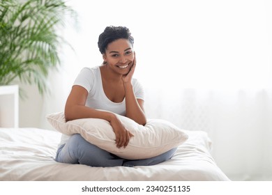 Cheerful Young African Woman Holding A Pillow And Sitting On The