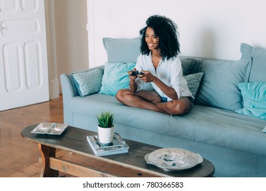 Beautiful Young Black Woman Seating In The Sofa Playing Video Games
