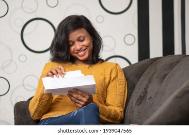 Beautiful Young Black Woman Smiling While Opening A Letter To Read