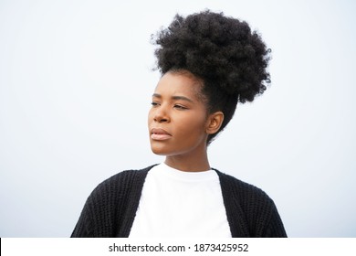 Beautiful Young Black Woman With Smooth Skin And An Updo High Puff Hairstyle Stands Against The Sky Looking Left                               