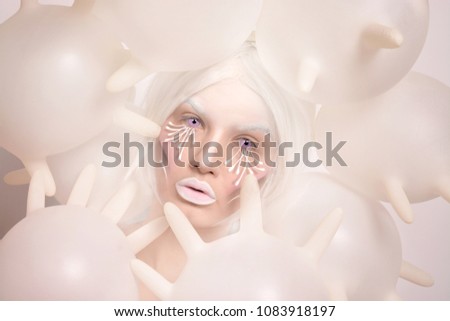 beautiful young blond girl with latex gloves around her face. pink lenses. 3d face painting with watercolor