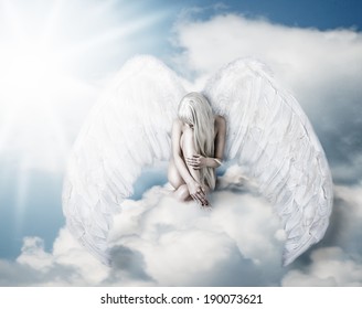 Beautiful young blond woman as angel sitting on a cloud, with white wings
