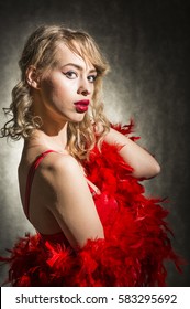 Beautiful Young Blond Woman Dressed In Red Sexy Dress And Red Feather Boa Scarf, Studio Shut On Black Background