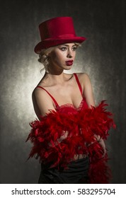 Beautiful Young Blond Woman Dressed In Red Sexy Dress, Red Feather Boa Scarf And Red Top Hat, Studio Shut On Black Background