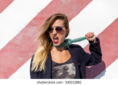 Beautiful Young Blond Woman With Glasses Pulling Himself For A Scarf Tied Around His Neck And Shouted His Mouth Open