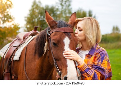 Beautiful Young Blond Woman Kisses Her Horse. The Concept Of Love For Nature, Human Interaction With Nature And Animals.