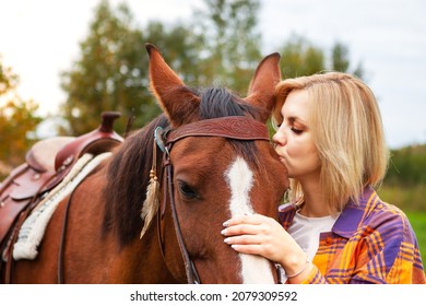 Beautiful Young Blond Woman Kisses Her Horse. The Concept Of Love For Nature, Human Interaction With Nature And Animals.