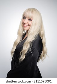 A Beautiful Young Blond Woman With A Long Wavy Hair In A Silky Robe, With A Glowing Skin, Isolated On A Grey Background