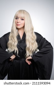 A Beautiful Young Blond Woman With A Long Wavy Hair In A Silky Robe, With A Glowing Skin, Isolated On A Grey Background