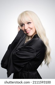 A Beautiful Young Blond Woman With A Long Wavy Hair In A Silky Robe, With A Glowing Skin, Isolated On A Grey Background