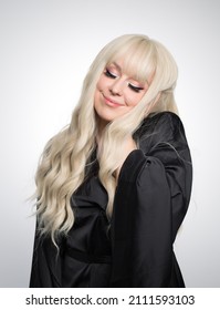 A Beautiful Young Blond Woman With A Long Wavy Hair In A Silky Robe, With A Glowing Skin, Isolated On A Grey Background