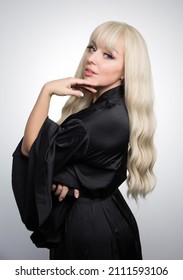 A Beautiful Young Blond Woman With A Long Wavy Hair In A Silky Robe, With A Glowing Skin, Isolated On A Grey Background