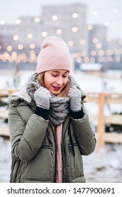 beautiful young blond woman on the Christmas market on lights background, New year concept, holiday mood. city holiday. girl in a knitted scarf and gloves on the background of the city.