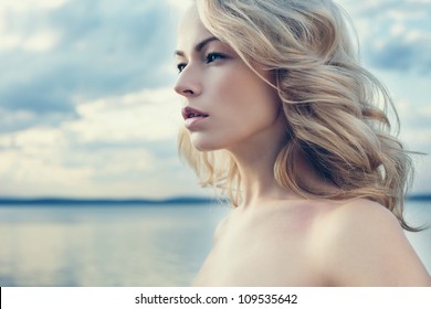 Beautiful young blond woman outdoors portrait near the lake