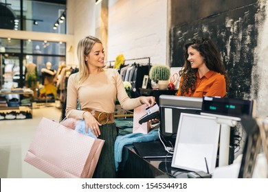 Beautiful Young Blond Woman Paying Her New Clothes Buyed In Expensive Boutique With Credit Card.